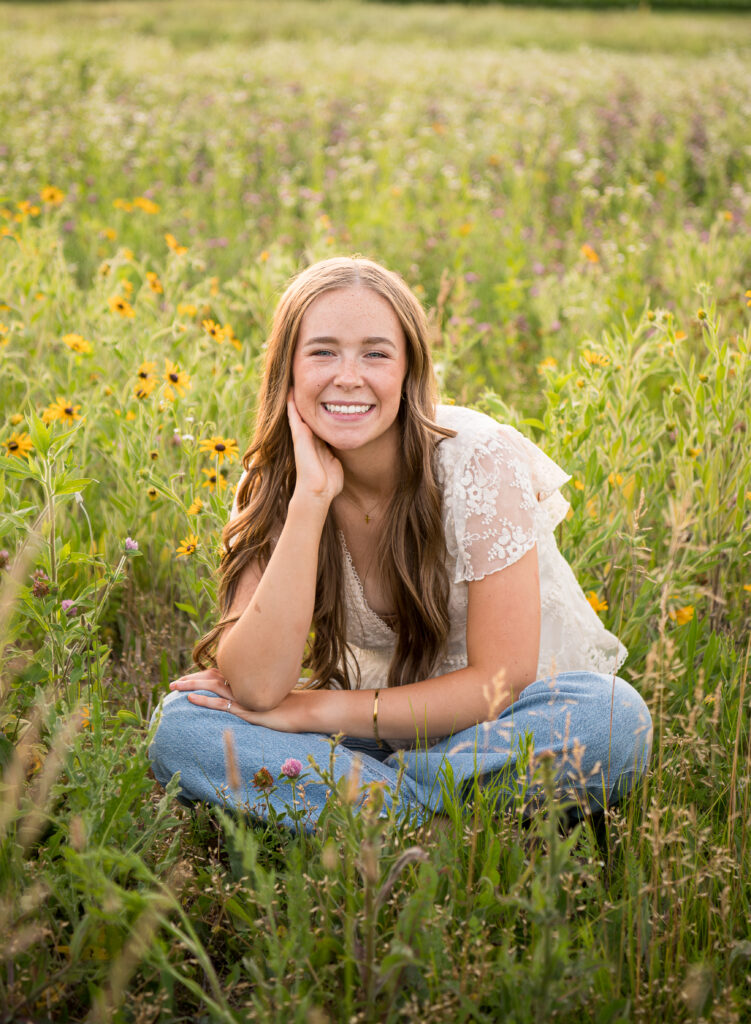 Senior portrait of Lilly in a wildflower field at sunset
